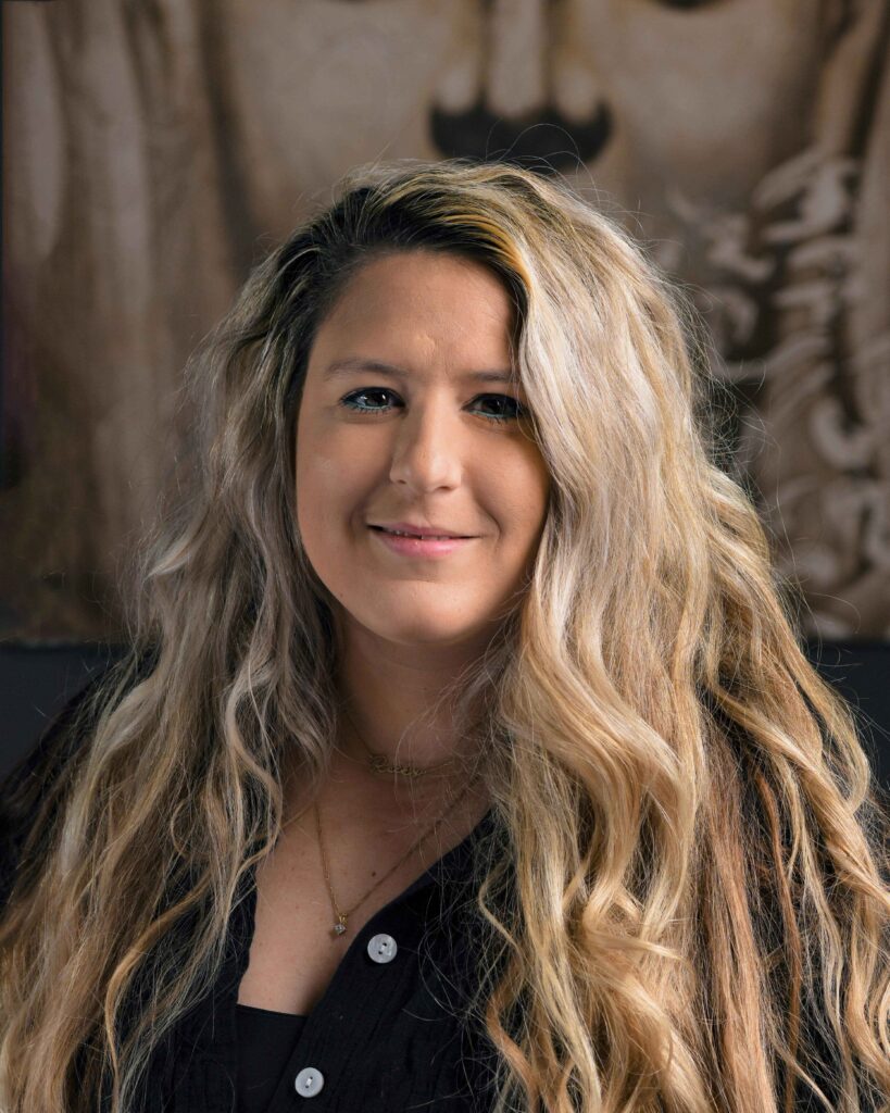 a woman with long blonde hair standing in front of a painting