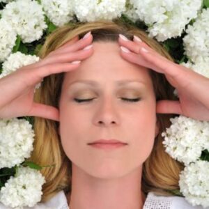 a woman holding her head in front of white flowers